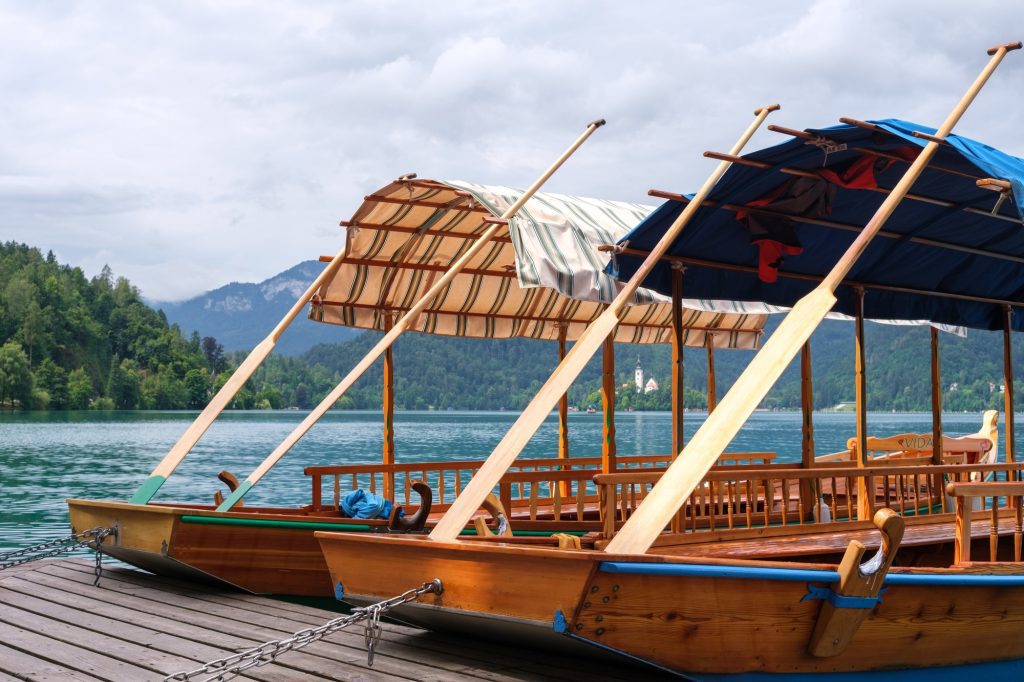 Pletna boats waiting by the shore – a scenic stop on the Lake Bled walking tour.